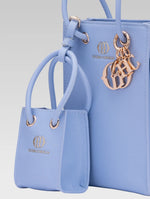 Load image into Gallery viewer, Cropped side view of genevieve bucket bag in baby blue color and a mini tote bag
